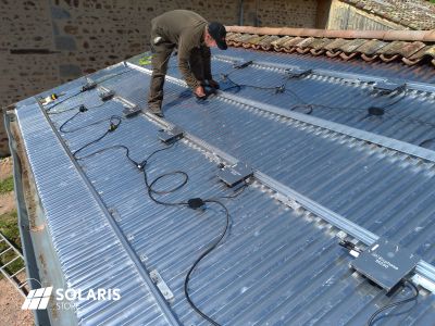 Installateur agréé SOLARIS posant des panneaux solaires en autoconsommation sur le toit d'un garage dans le Beaujolais